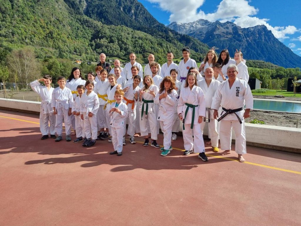 Stage FTK Olivone 2024: gruppo in gi posa sul terrazzo esterno con le montagne sullo sfondo